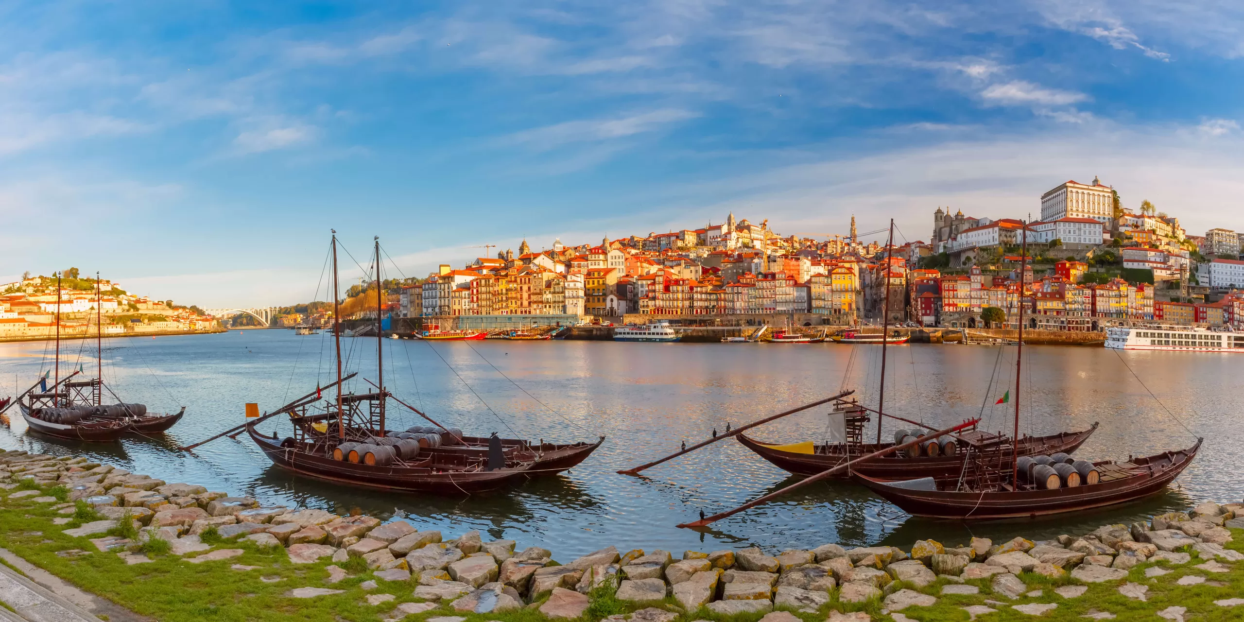 panoramic-view-of-traditional-rabelo-boats-with-barrels-of-port-wine-on-the-douro-river-ribeira-on-the-background-porto-portugal